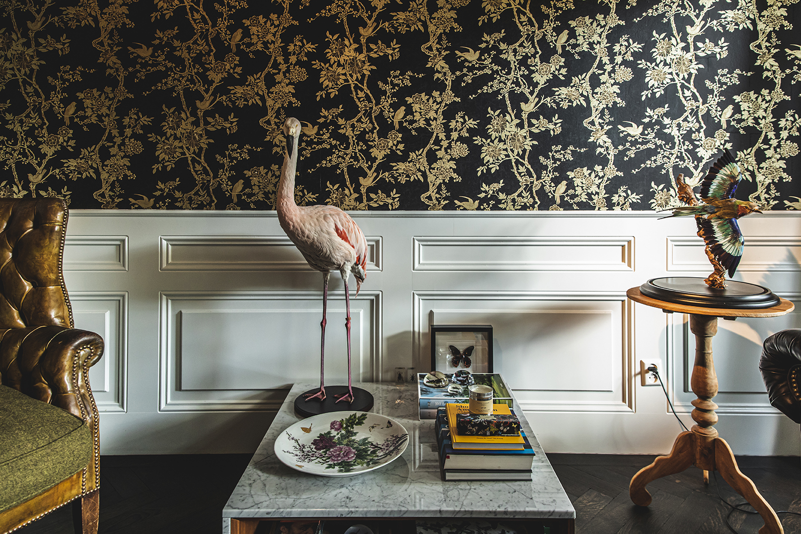 A flamingo sculpture against dark floral wallpaper