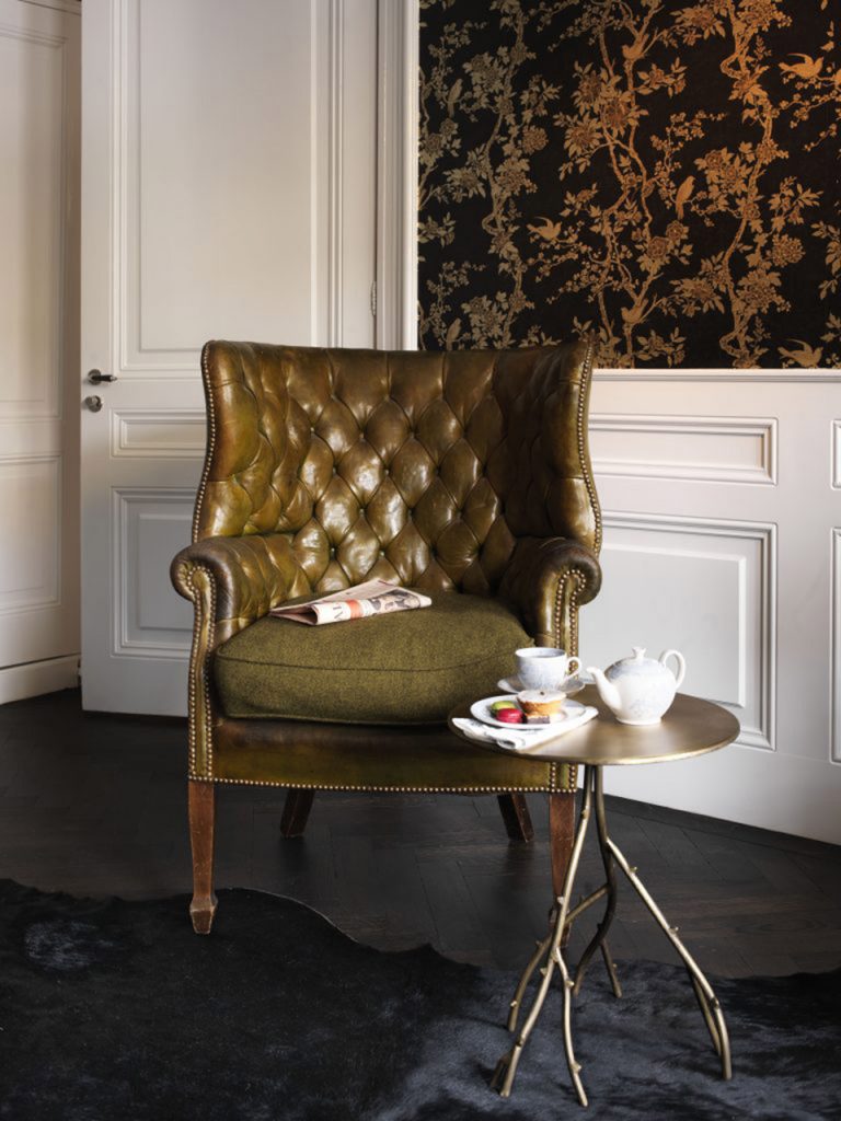 An olive chesterfield chair with a tea tray